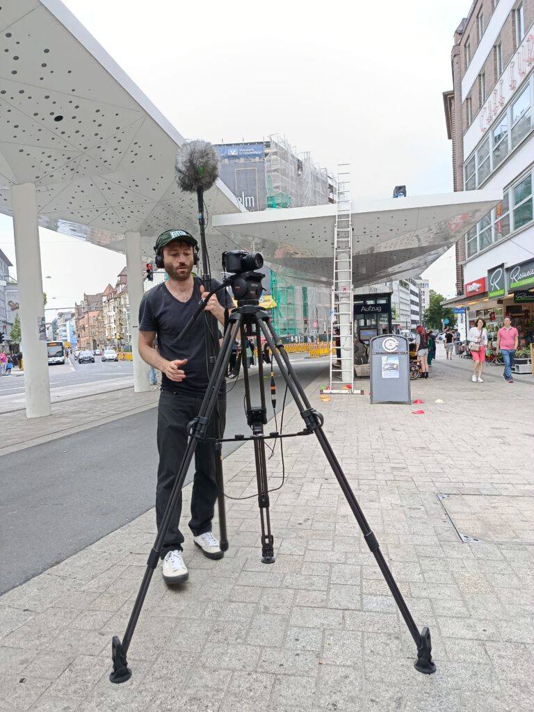 Topos One bei der Arbeit mit Kamera auf Stativ und Tonangel, Jahnplatz, Bielefeld